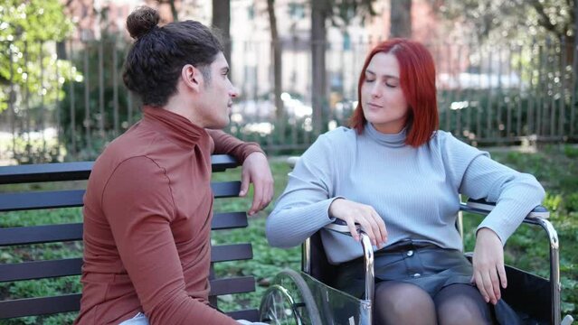 complicity, affection-man takes hand of his disabled girlfriend looking at her 