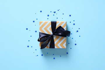 Vintage gift box with blue ribbon bow on pastel blue background with confetti stars. Happy Fathers...