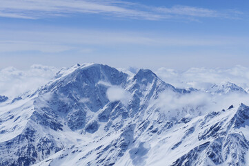 Fototapeta na wymiar Panoramic view on snow mountain peak with clouds and blue sky, Elbrus