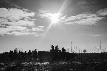 Silhouette of a group of soldiers and tank sun background at sunset. Preparation of modern military to battle