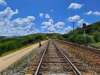 Fototapeta na wymiar Train station . Industrial landscape with railway, blue sky with clouds in summer. Rail transport, train tracks, rural scene in Minas Gerais, Brazil.