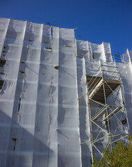A mansion under renovation with scaffolding against the blue sky. Concept of renovating. Superbonus 110 in Italy. Vertical image.