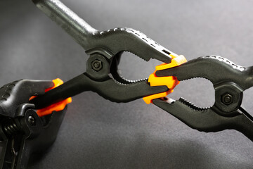 Selective focus of plastic clamps holding each other on black isolated background. Another clamp is...