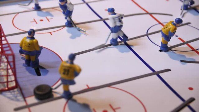 Playing tabletop hockey with tiny plastic figures and puck in light room closeup. Interesting sports toy for children and adults