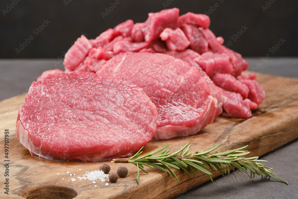 Wall mural Fresh cut of beef on a wooden board with salt, pepper, rosemary. Raw steak beef meat fillet ready to cook. Selective focus