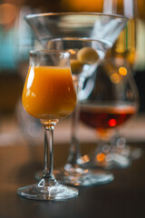 a small glass with an orange cocktail