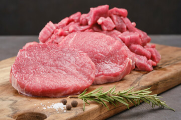 Fresh cut of beef on a wooden board with salt, pepper, rosemary. Raw steak beef meat fillet ready to cook. Selective focus