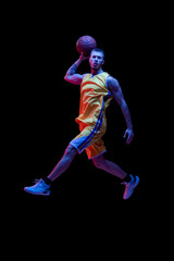 Fototapeta na wymiar Portrait of sportive man, professional basketball player playing basketball isolated on dark background in neon light. Achievements, sport career, motion concepts.
