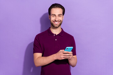 Photo of young cheerful influencer guy chatting with friends in telephone isolated on purple color...
