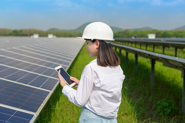 Female engineer wearing helmet in Photovoltaic Cell Farm or Solar Panels Field, eco friendly and clean energy.