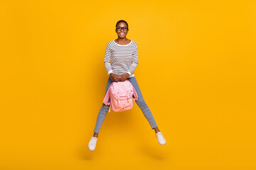 Full size photo of young cheerful girl jump up hold bag travel trip isolated over yellow color background