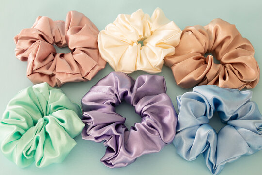 Collection of trendy silk elastic bands scrunchies on blue background. Diy accessories and hairstyles concept, luxury color