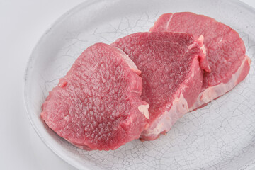 Fresh cut of beef in a white plate. Raw steak beef meat fillet ready to cook. Selective focus