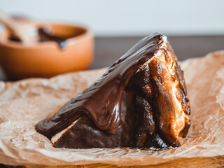 Appetizing piece of Basque burnt cake topped with hot chocolate. Freshly baked san sibastian dessert on a wooden table