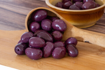 purple olives in a bowl on a wooden board