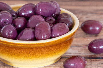 purple olives in a bowl on a wooden board