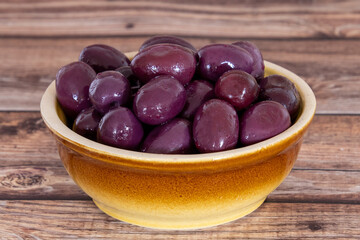 purple olives in a bowl on a wooden board