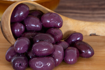 purple olives in a bowl on a wooden board