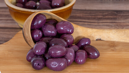 purple olives in a bowl on a wooden board