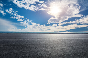 Empty asphalt road and sky clouds with lake background at sunset