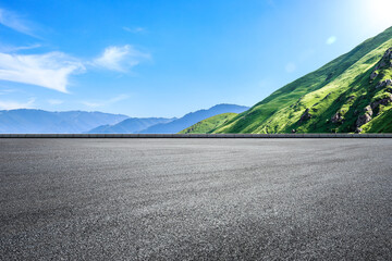 Empty asphalt road and green mountain nature landscape under blue sky. Road and mountains background. - obrazy, fototapety, plakaty