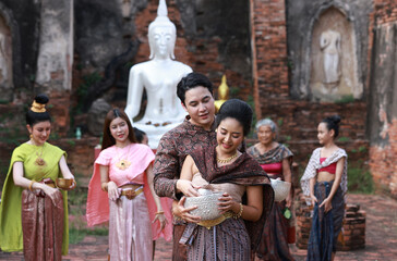 Naklejka premium Asia group peple wearing Thai Traditonal dress plash water to each other , celebrate Songkran festival at Choengthar Temple , Ayuthaya of Thailand