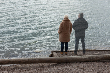 Lonely woman standing by the lake with ghost of a man standing by her side, staring in the distance