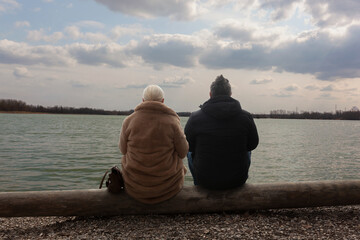 Couple, man and woman sitting by the lake, staring in the distance