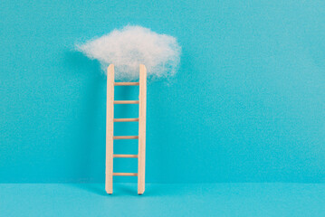 Ladder with a cloud on top, blue colored background, copy space, dreaming of success, creative and...