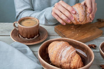 The girl drinks coffee and eats croissants. Fragrant stimulating drink. Fresh bakery. Breakfast, snack.