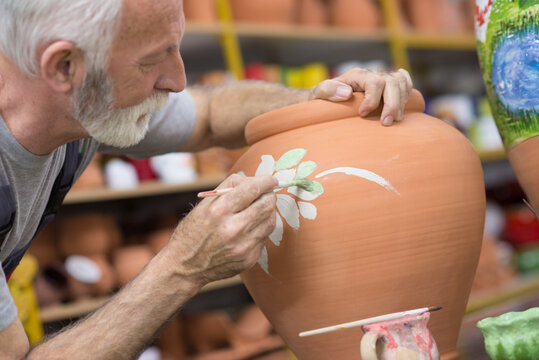 Senior craftsman potter making pottery in his workshop