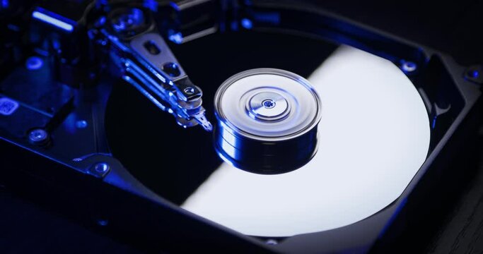 Hard disk drive HDD is working. Spinning up a disk with blue light. Computer parts.