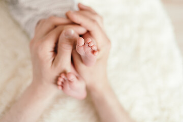 Fototapeta na wymiar small legs of a newborn baby in the hands of his father. close-u
