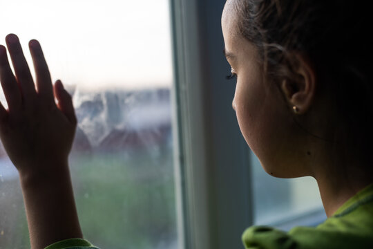 Child Girls Are Standing In The Dark, Looking Out The Window, Sad Mood