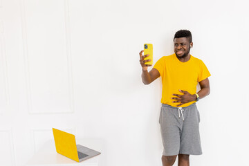 Handsome Afro American man in trendy yellow sportswear, does exercise or push-ups, stands on arms...