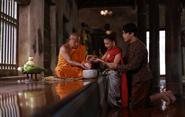 A couple Sprinkle water onto Monk, Make merit on Songkran festival day for prosperity and good luck