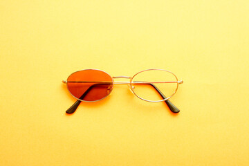 Sunglasses with one missing lens on yellow background.