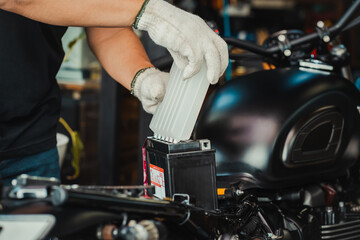 mechanic replaces motorcycle battery and holding Acid pack or sealed battery electrolyte pack to...