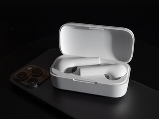 White wireless headphones and telephone on a black background.