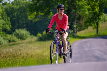 Closeup of smiling woman wearing bike helmet looking aside biking on a country road on a spring summer day.