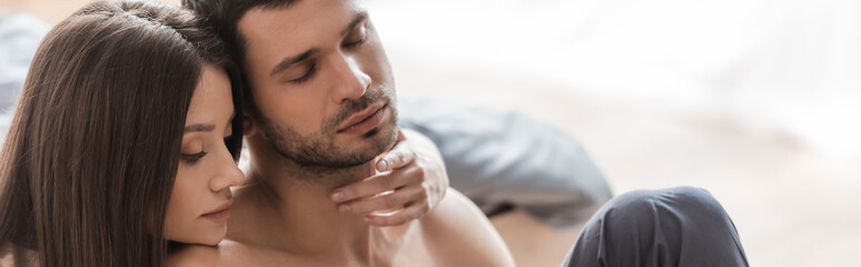 Obraz premium Young woman touching neck of shirtless man in bedroom, banner.