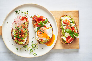 Vegetarian egg sandwiches on white background.. Healthy vegetarian sandwiches with egg tomatoes avocado cream and cheese garnished with chia seeds and aromatic herbs. Vegetarian sandwich.