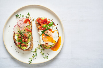 Vegetarian egg sandwiches on white background.. Healthy vegetarian sandwiches with egg tomatoes avocado cream and cheese garnished with chia seeds and aromatic herbs. Vegetarian sandwich.