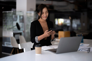 Fototapeta premium Business asian woman using mobile phone during checking an email or social media on internet. accounting financial concept.