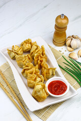 Siomay Goreng or Pangsit Goreng, Indonesian popular street food, made from fish and shrimp wrapped with dumpling wrapper, deep fried, served with chili sauce or peanut sauce. Selective focus. 