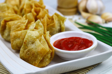 Siomay Goreng or Pangsit Goreng, Indonesian popular street food, made from fish and shrimp wrapped with dumpling wrapper, deep fried, served with chili sauce or peanut sauce. Selective focus. 