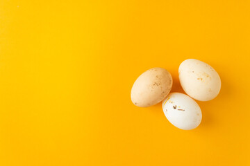 Three natural farm chicken eggs isolated on yellow background. Easter holiday concept.