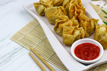 Siomay Goreng or Pangsit Goreng, Indonesian popular street food, made from fish and shrimp wrapped with dumpling wrapper, deep fried, served with chili sauce or peanut sauce. Selective focus. 