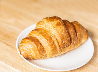 An image croissant a bake on the white dish is a food delicious brunch background on the table.