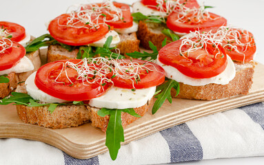 Open sandwiches with fresh mozzarella, tomatoes and arugula. Italian food concept
